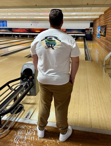 A man stands at a bowling lane, preparing to bowl.