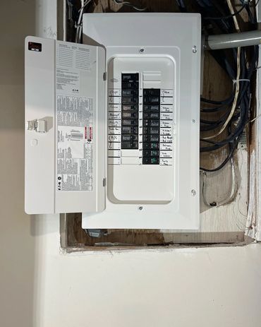 Open electrical panel with labeled circuit breakers and exposed wiring.