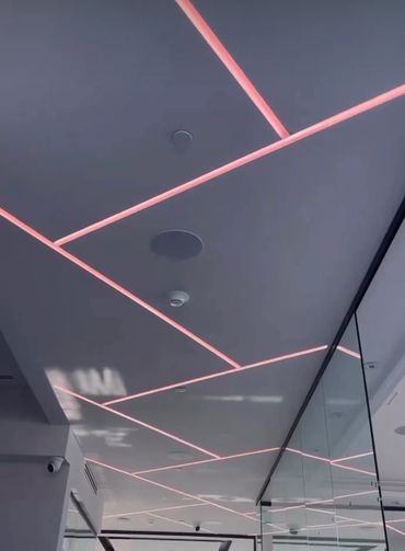 Modern ceiling with pink LED strip lights creating geometric patterns.