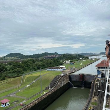 View of the Panama Canal lock system with gates, water channel, and surrounding green landscape.