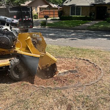 A stump grinding machine removing a tree stump in a residential yard.