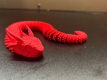 A detailed red dragon sculpture with textured scales on a dark surface.