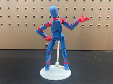 3D-printed blue and red articulated figure on a white stand.