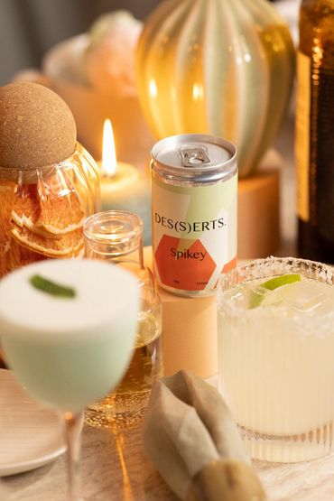 bespoke canned whisky cocktail called DES(S)ERTS next to candle and colourful table props