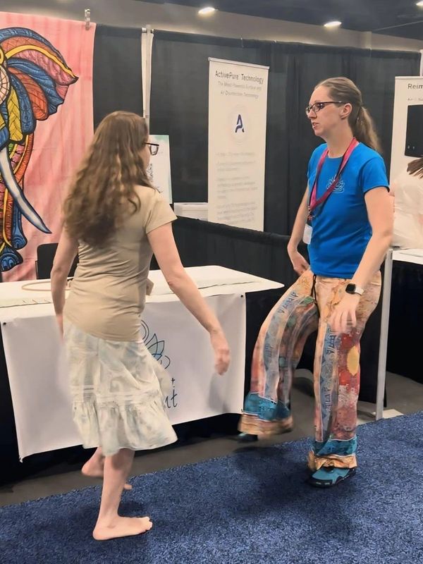 Angie Berrett teaching playful movement to a participant at a event booth.