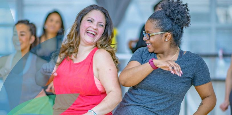 Two women laughing and dancing together, exuding joy and energy.