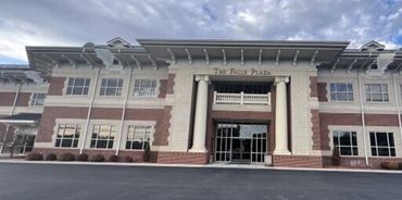 Front view of The Falls Plaza building under a cloudy sky.