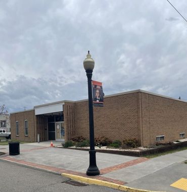 A brick building with a street lamp and a cloudy sky.