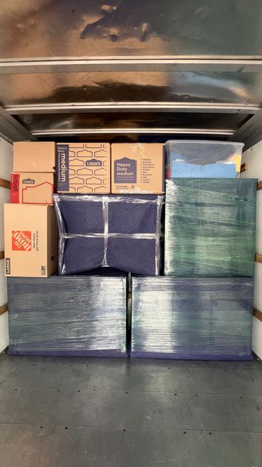 Neatly packed moving boxes and wrapped furniture inside a truck.