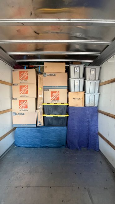 Neatly packed moving boxes and storage bins inside a truck.