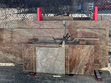 Various large slabs of polished stone leaning against a fence outdoors.