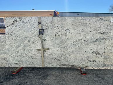Large slabs of granite stone displayed outdoors on a sunny day.