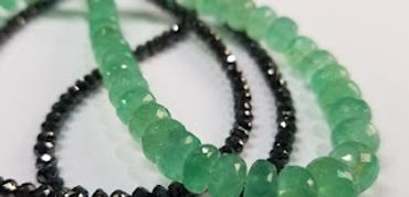 Close-up of green and black beaded bracelets on a white surface.