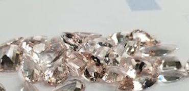 A collection of cut gemstones on a white surface with a ruler.