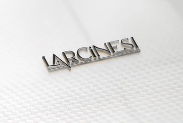 3D metallic text of the word 'LARCINES!' on a textured white surface.