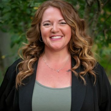 Smiling woman with wavy hair outdoors.