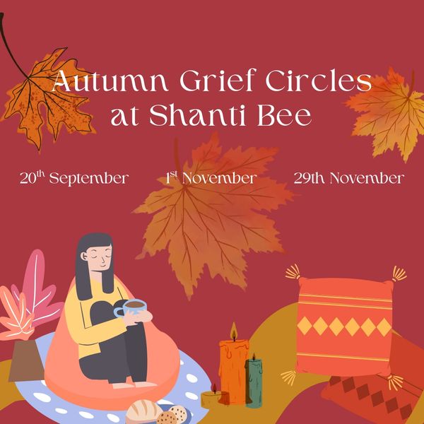 A person sitting on a beanbag with a tea, next to cushions and candles with autumn leaves falling