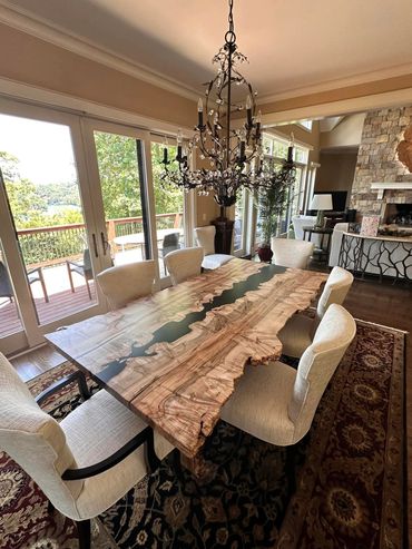 Live edge river table with white chairs in a dining room setting.
