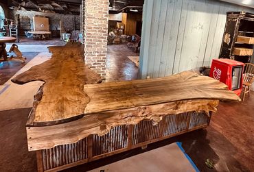 Live edge check out counter with rusty tin panels and live edge trim inside a store.