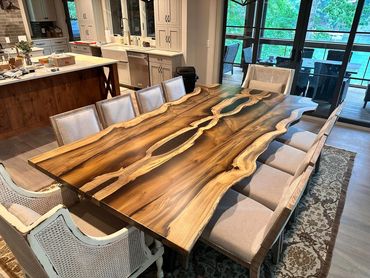 Magnolia live edge table with resin center. White cloth chairs. Room has cabinets and island .