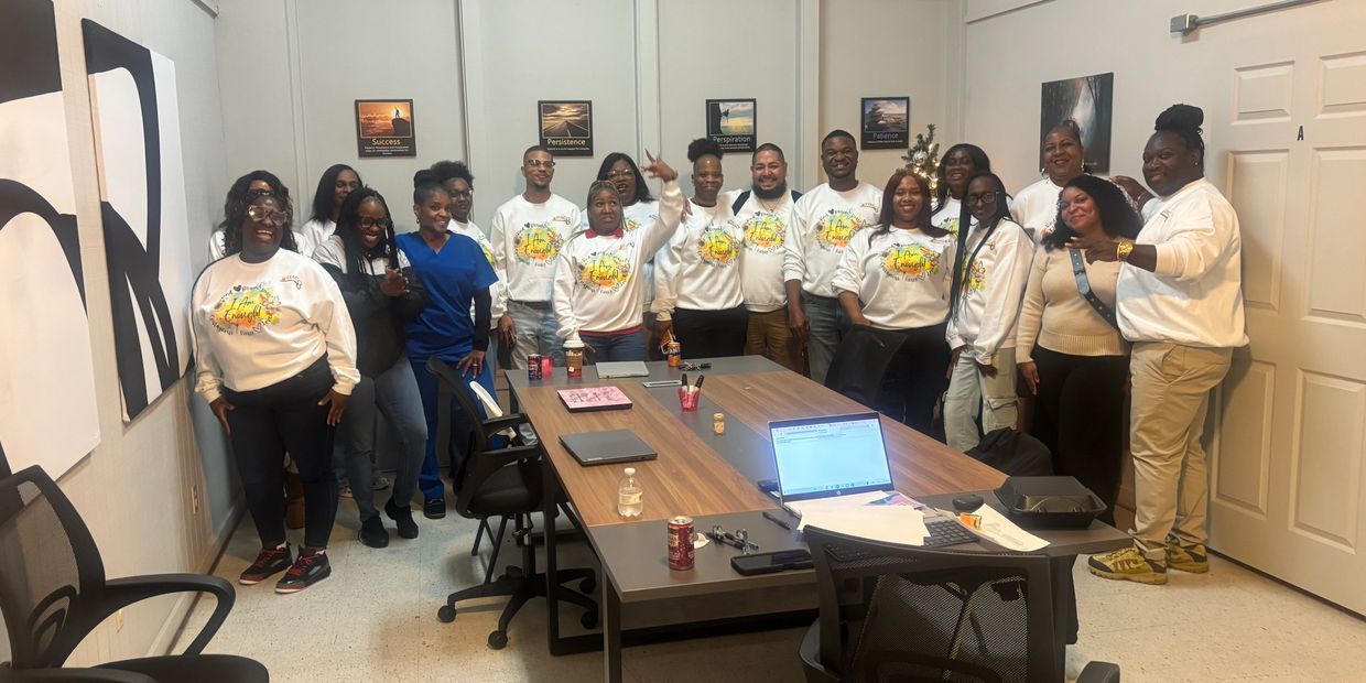 Group photo of people in matching white sweatshirts in a meeting room.