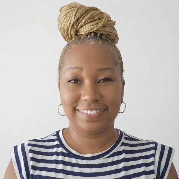 Smiling woman with braided hair in a striped shirt against a white background.