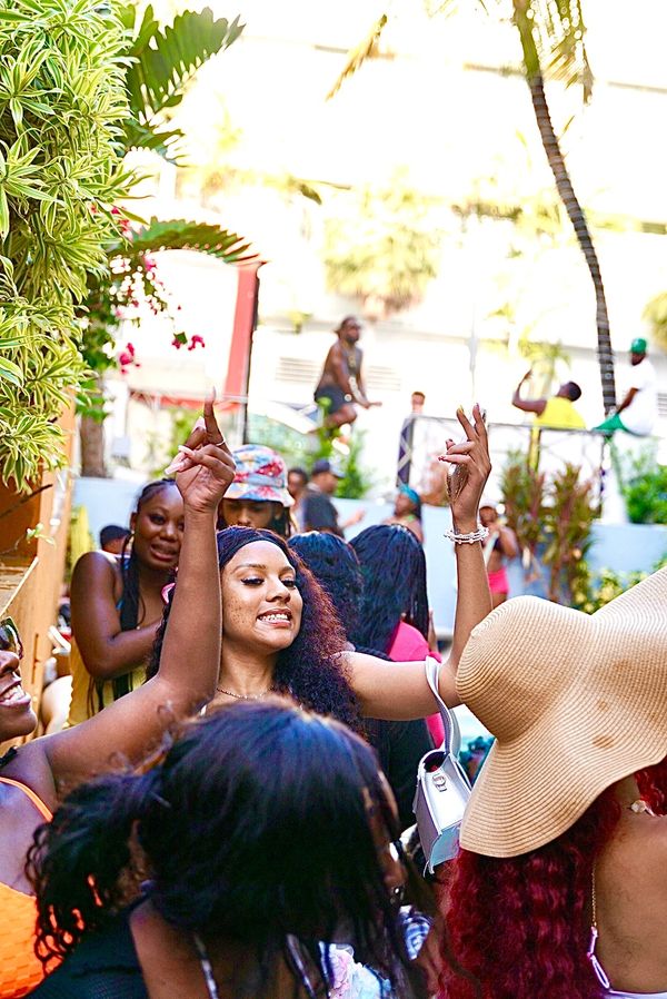 A joyful group of people dancing and celebrating outdoors under the sun.