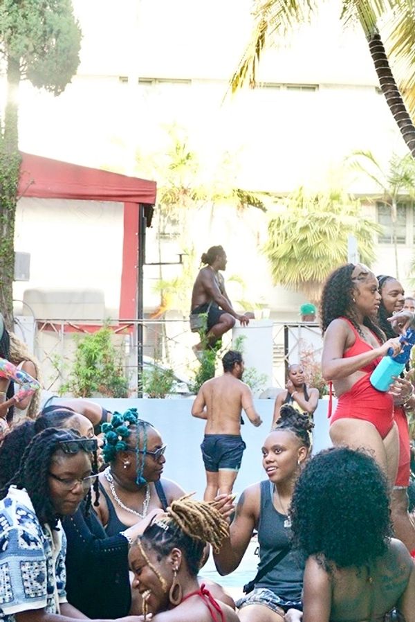 Group of women enjoying a lively pool party under palm trees.