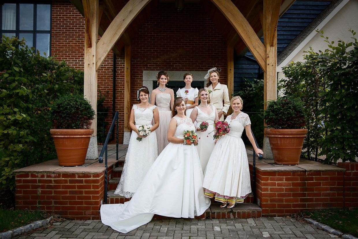7 models standing on steps outside venue wearing various wedding dresses by Susie Grist Couture