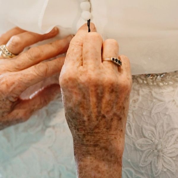 Mums hands doing up button fastening on daughters wedding dress