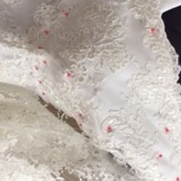 Lace fabric being pinned to the satin bodice of a wedding dress made by Susie Grist Couture