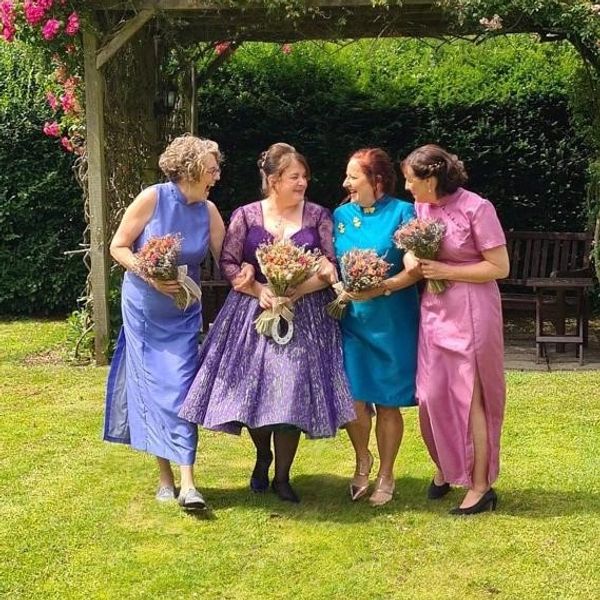 Bride in 1950's purple wedding dress with her three bridesmaids