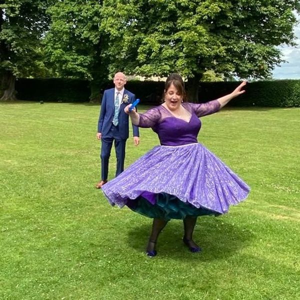 Bride twirling in her purple 1950's wedding dress being watched by groom