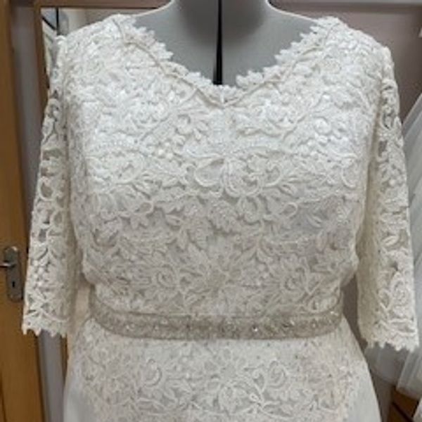 Front bodice of wedding dress on tailors dummy. V-neck Guipure lace with beaded trim at waist
