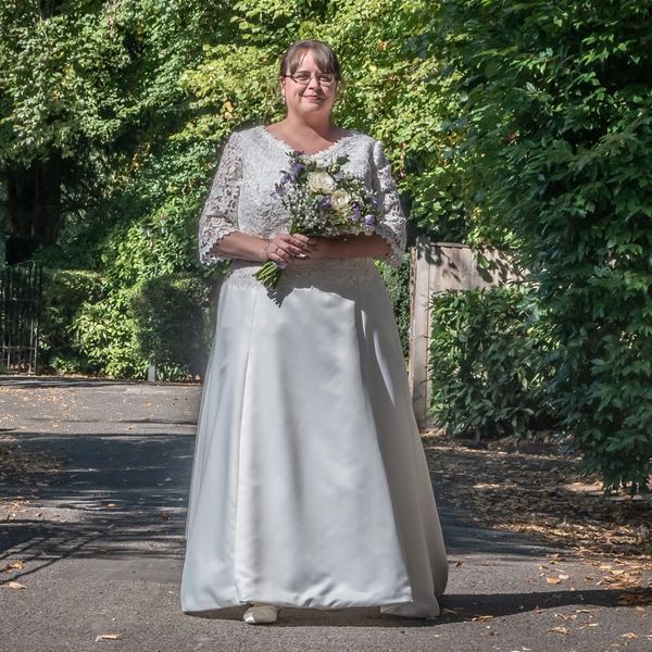 Bride walking over bridge in her bespoke lace and satin wedding dress by Susie Grist Couture