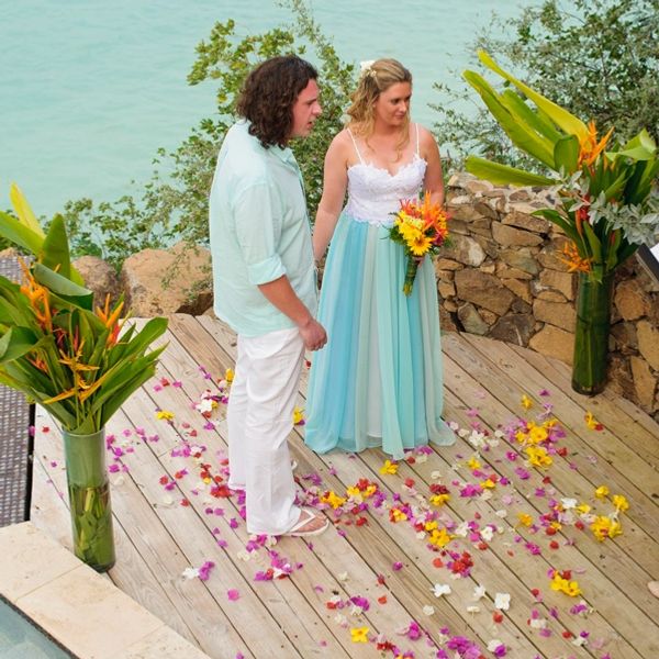 Bride and groom holding hands during service outside by a pool on a tropical island