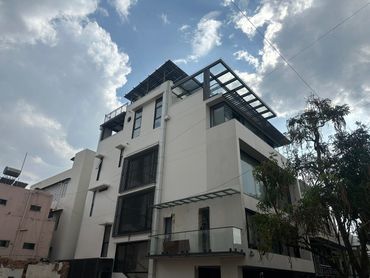 Modern white multi-story building with large windows and solar panels on the roof.