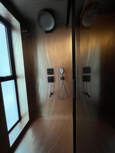 Modern shower area with sleek brown walls and a large window.