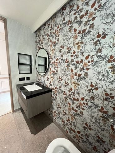 Bathroom with floral wallpaper and a floating vanity with a round mirror.