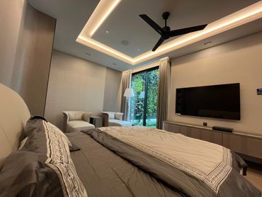Modern bedroom with a large bed, two chairs, and a wall-mounted TV.