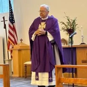 A priest in purple vestments standing inside a church.