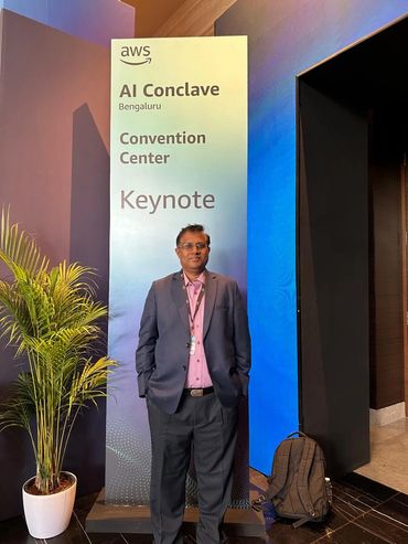 Man standing in front of AWS AI Conclave Bengaluru banner.