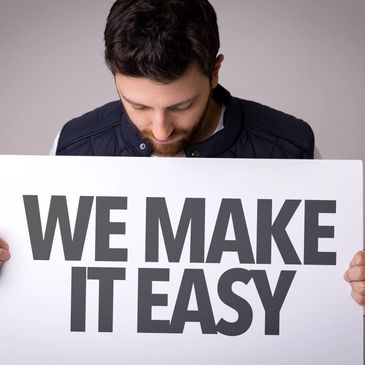 Man holding a sign that says 'WE MAKE IT EASY'.