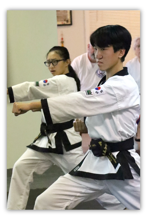 Two Tang Soo Do / martial arts black belt students performing punch in karate studio
