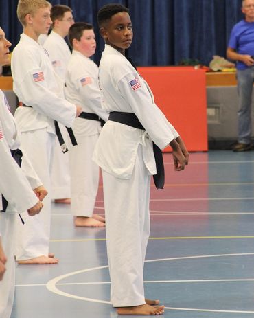 Black belt child standing awaiting instruction