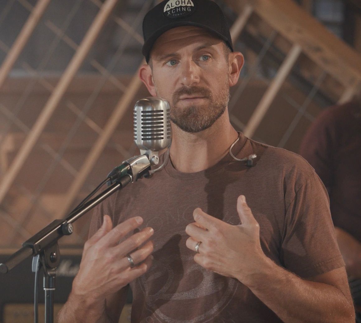 Man speaking into a vintage microphone with focus and gestures.