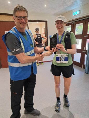 Runner Chloe receives award from event crew member.