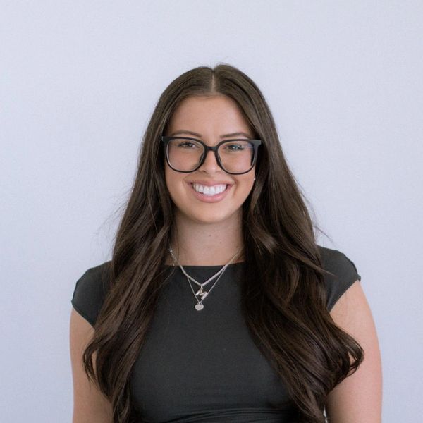Smiling woman with long hair and glasses.