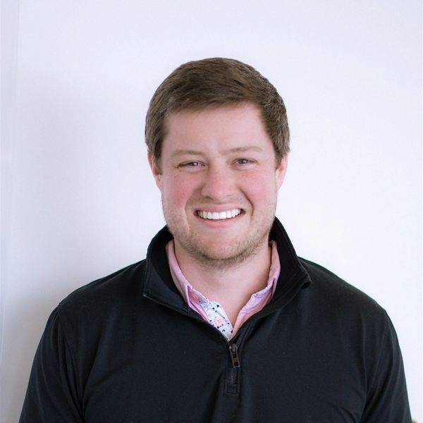 Smiling man in black quarter-zip sweater.