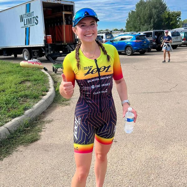 Woman that just completed a triathlon and is giving a thumbs up